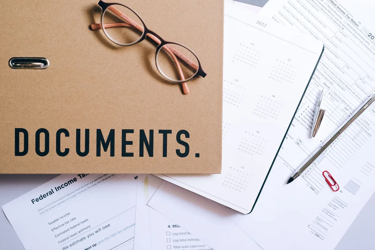 Eyeglasses, a documents folder and tax forms on a desk