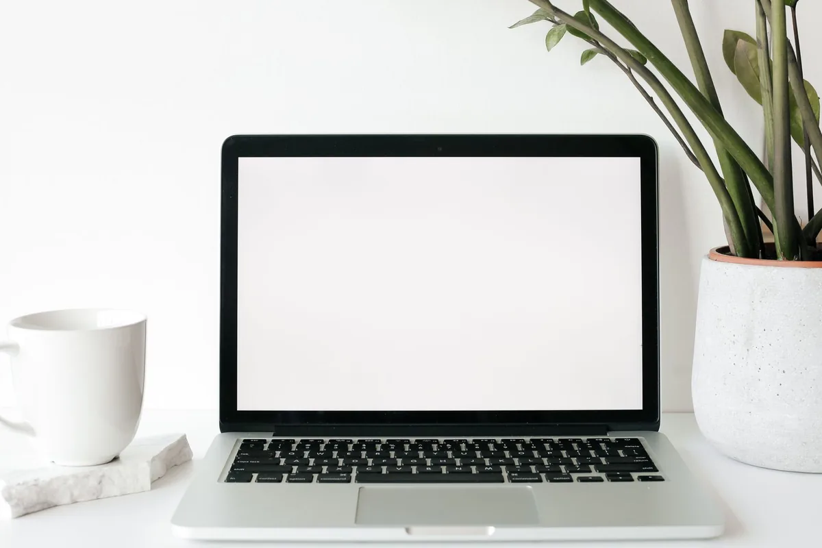 A home office desk with a laptop, notebook and coffee